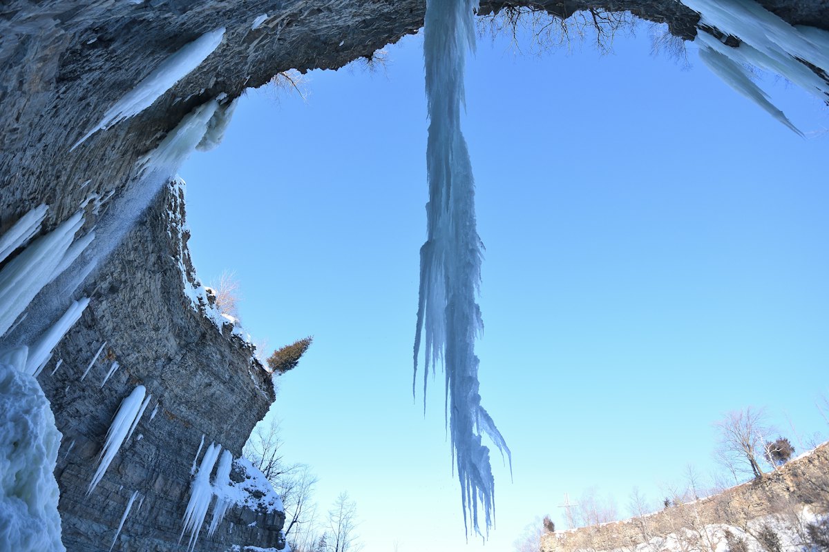 Colonne di ghiaccio azzurro che scendono da una roccia contro il cielo